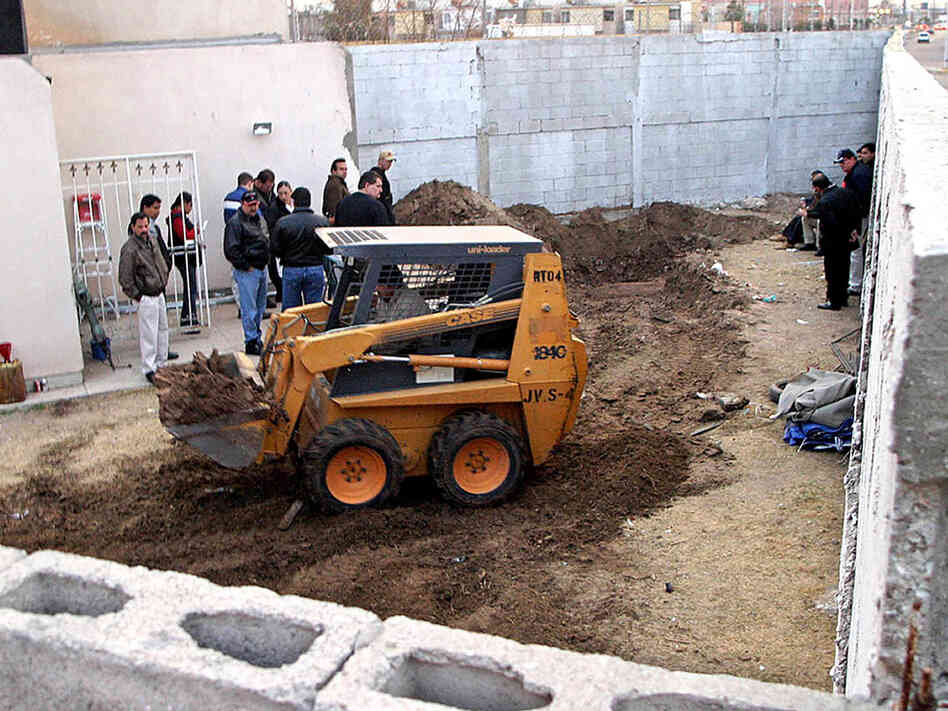 Members of the Federal Agency of Investigations excavate the yard at the House of Death.