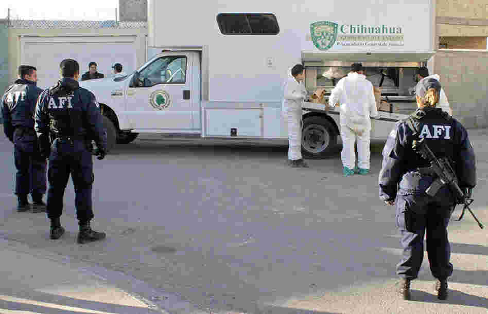 Mexican law enforcement officials load a corpse found at a Juarez drug cartel's house in 2004.