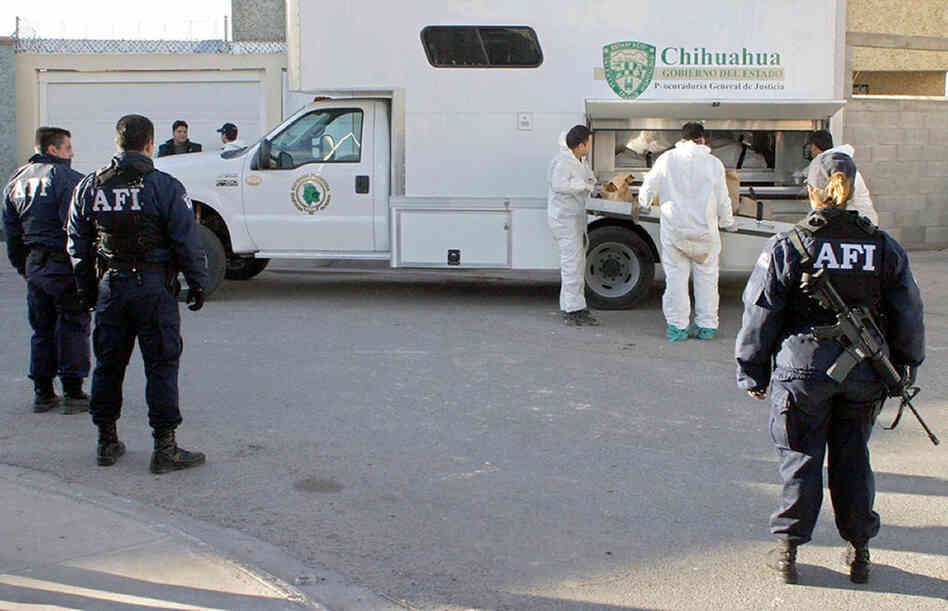 Mexican law enforcement officials load a corpse found at a Juarez drug cartel's house in 2004.