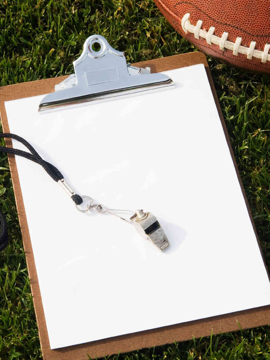 A football, clipboard, and whistle laying on the grass A football, clipboard, and whistle laying on the grass