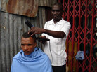 Barber Luxon Fanfan cuts customer Cadelis Dennis' hair outside. Barber Luxon Fanfan cuts customer Cadelis Dennis' hair outside.