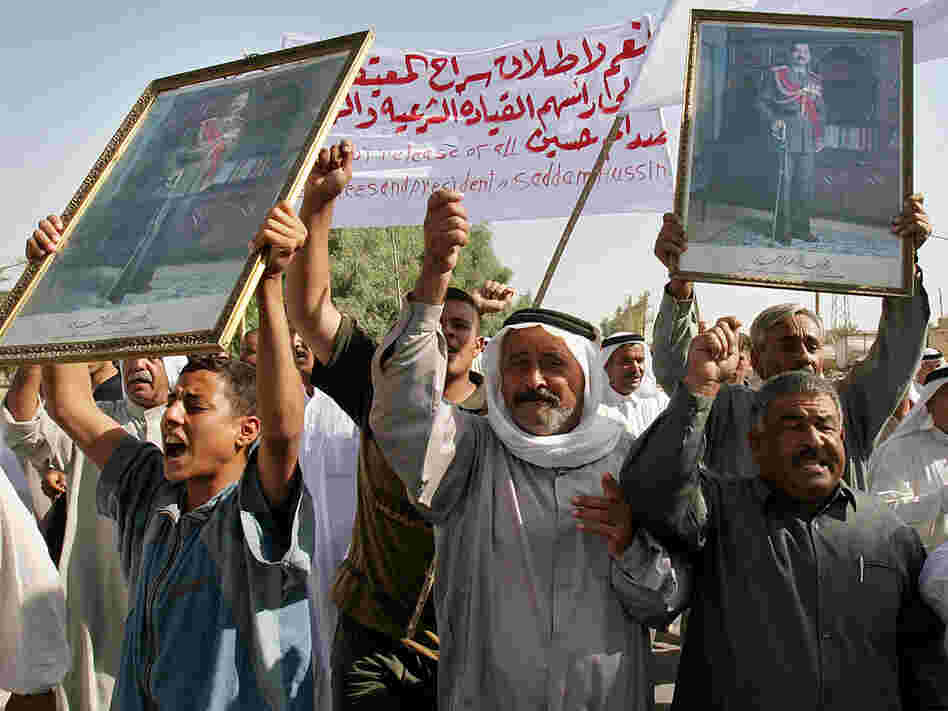 Iraqis holding pictures of Saddam Hussein march during a protest.