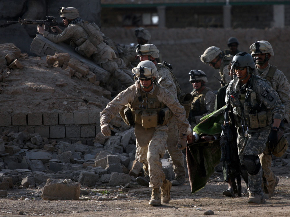 An Army flight medic and U.S. Marines carry a wounded Taliban on a stretcher amid a firefight