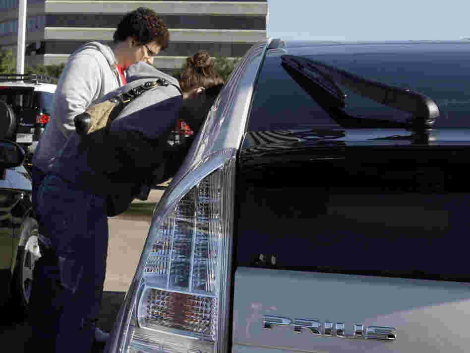 Customers look at a new Toyota Prius sedan.