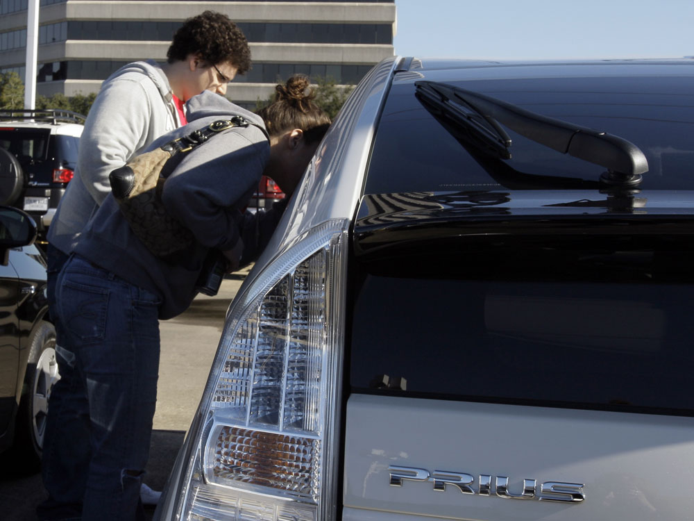 Customers look at a new Toyota Prius sedan.
