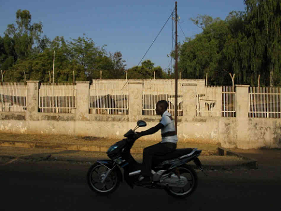 Motorcyclist drives in front of an abandoned American consulate compound.