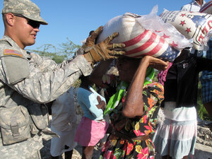 U.S. soldier hands out sacks of rice to Haitians in Cite Soleil