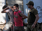 A soldier escorts two men detained for looting on Tuesday in the fishing village of Constitucion. A soldier escorts two men detained for looting on Tuesday in the fishing village of Constitucion.