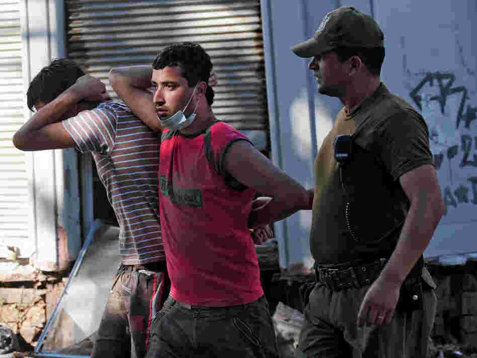 A soldier escorts two men detained for looting on Tuesday in the fishing village of Constitucion.