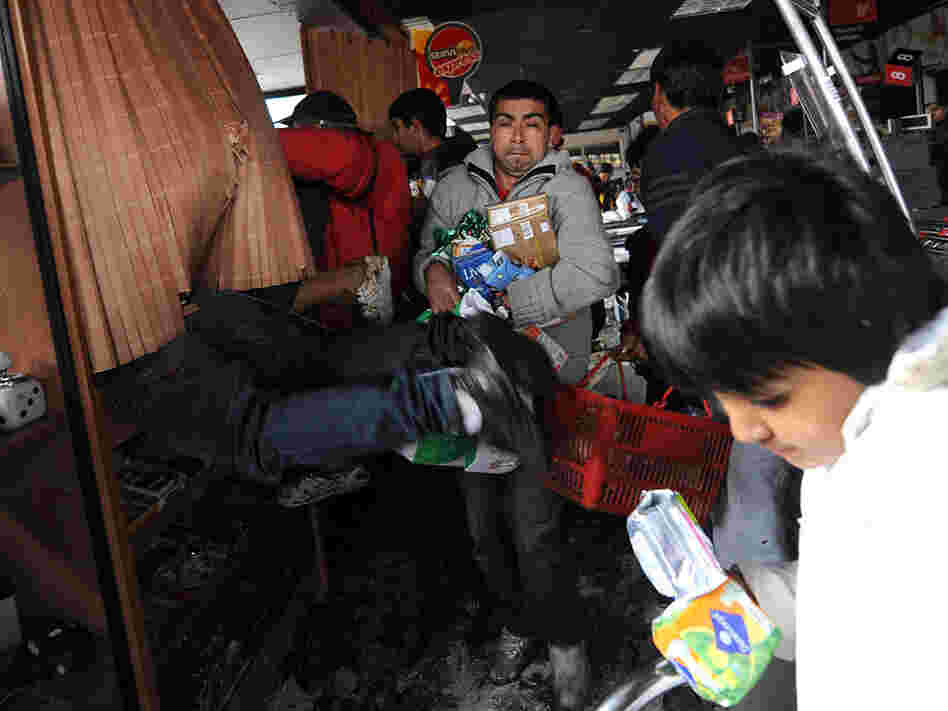 People are seen looting a supermarket Sunday in Penco, Chile.