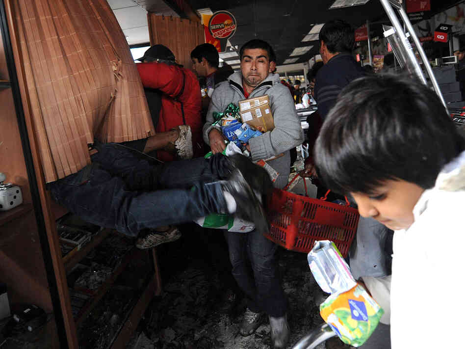 People are seen looting a supermarket Sunday in Penco, Chile.