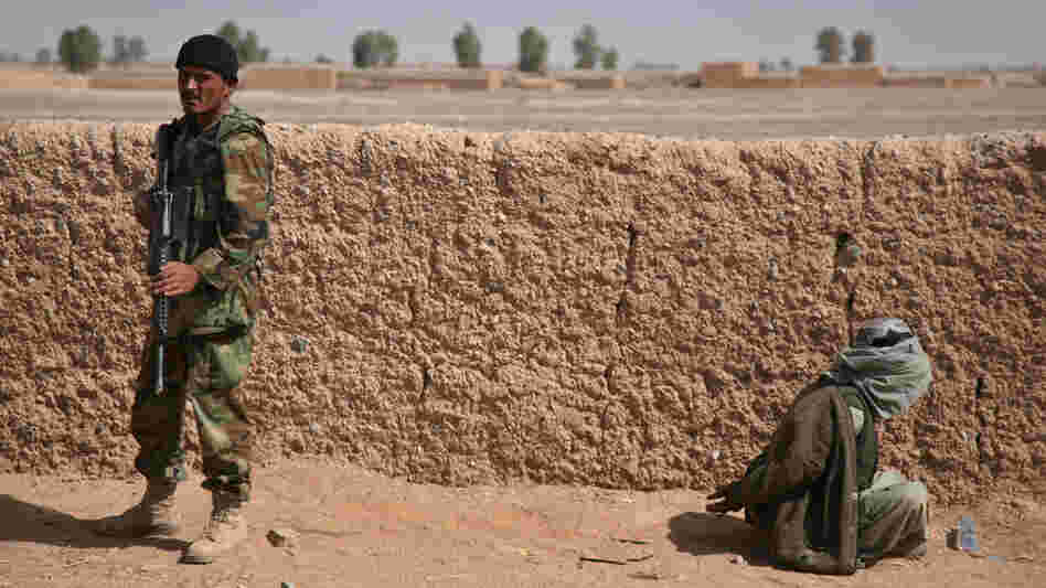 An Afghan National Army soldier stands guard over a blindfolded suspected Taliban fighter.