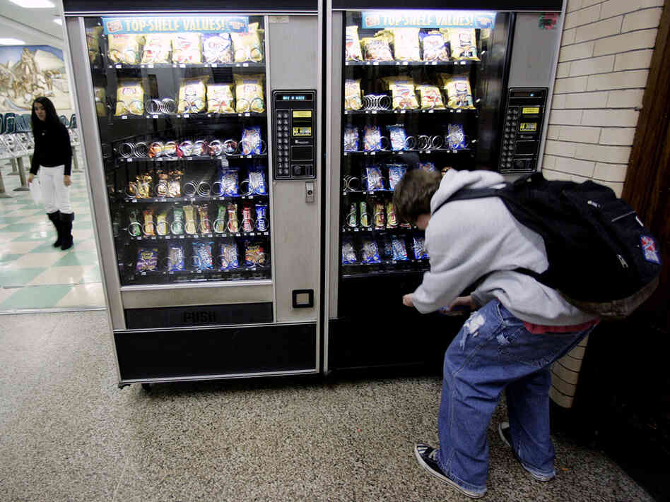 A student buys something from a vending machine.