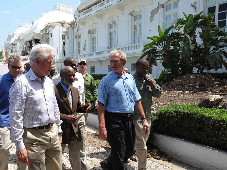 Former U.S. presidents George Bush and Bill Clinton walk with Haitian President Rene Preval.