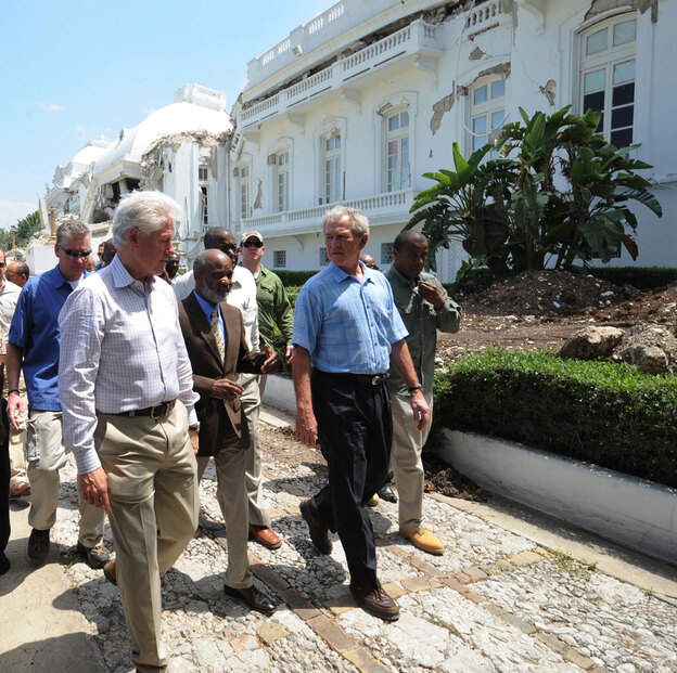 Former U.S. presidents George Bush and Bill Clinton walk with Haitian President Rene Preval.