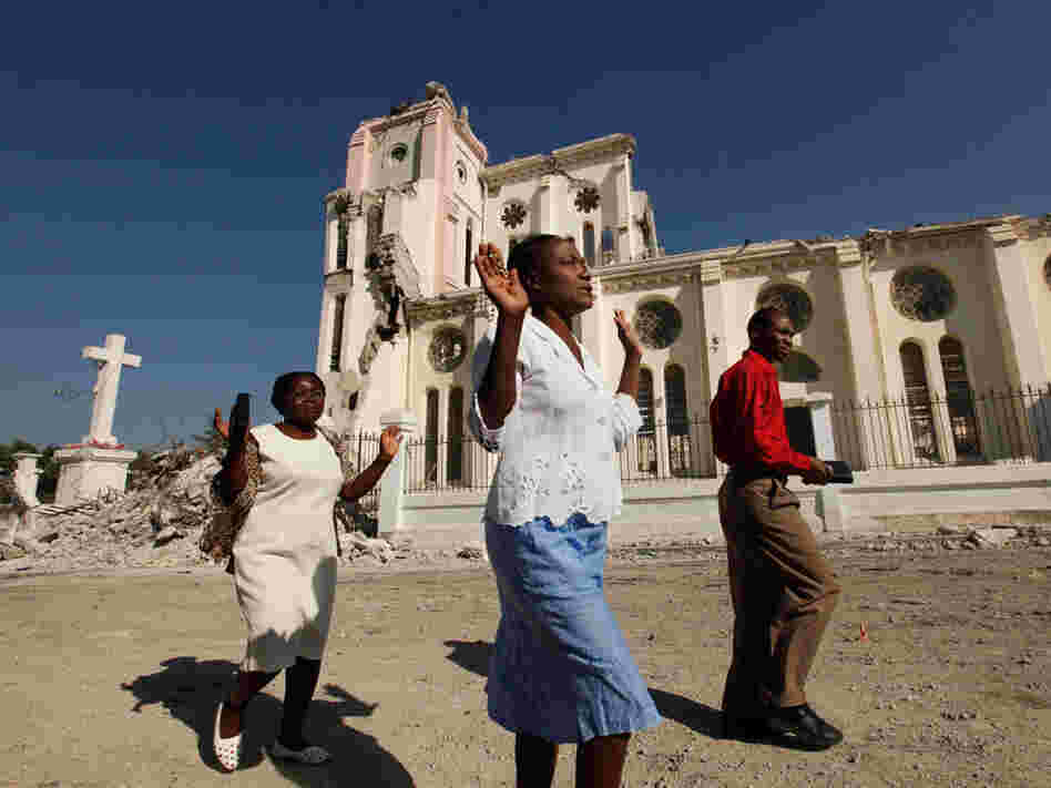 Haitians pray as they walk past the ruins of the National Cathedral.