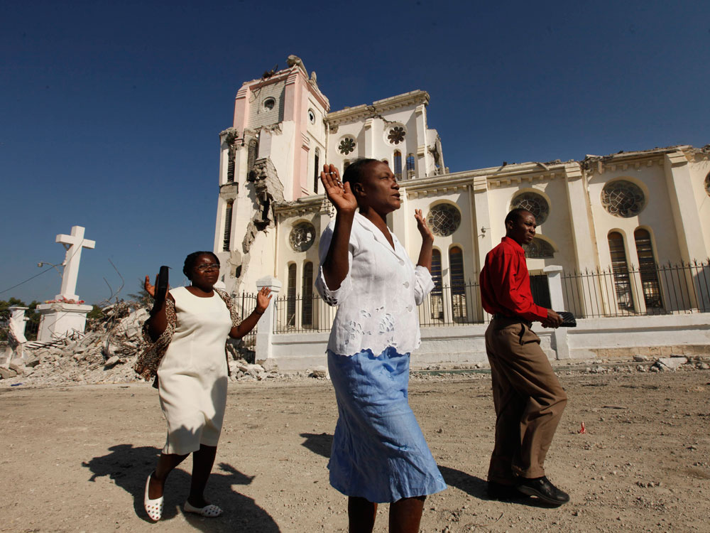 Haitians pray as they walk past the ruins of the National Cathedral.