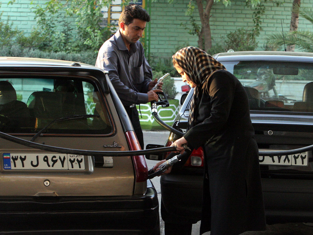 A woman and a man gas up their vehicles at a station in Tehran in 2007.