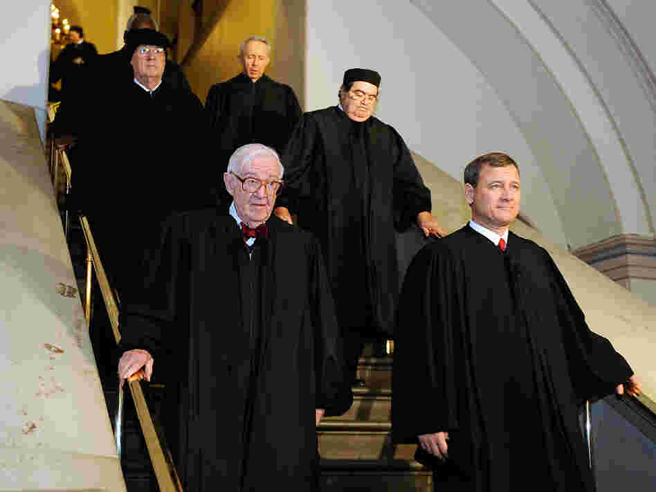 Supreme Court Justice John Paul Stevens and Chief Justice John Roberts walk with other justices.