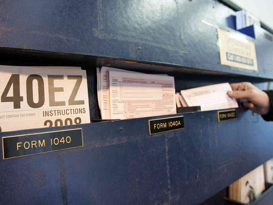 A man picks up federal tax Form 1040 at a post office.