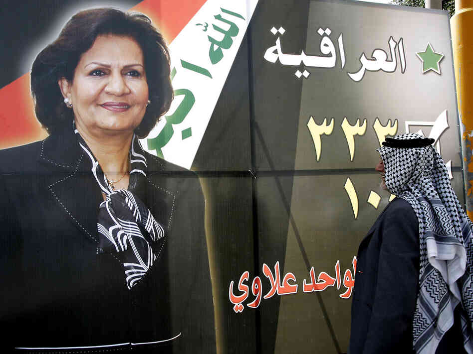 Man looks at poster of Iraqi woman candidate in March elections