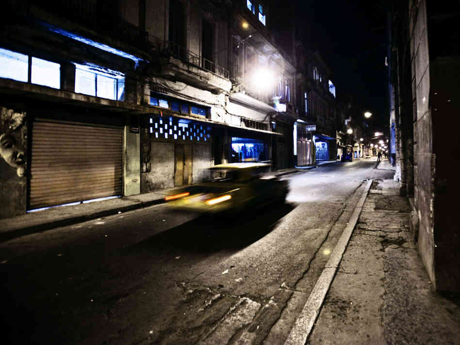 A taxi on a dark street.