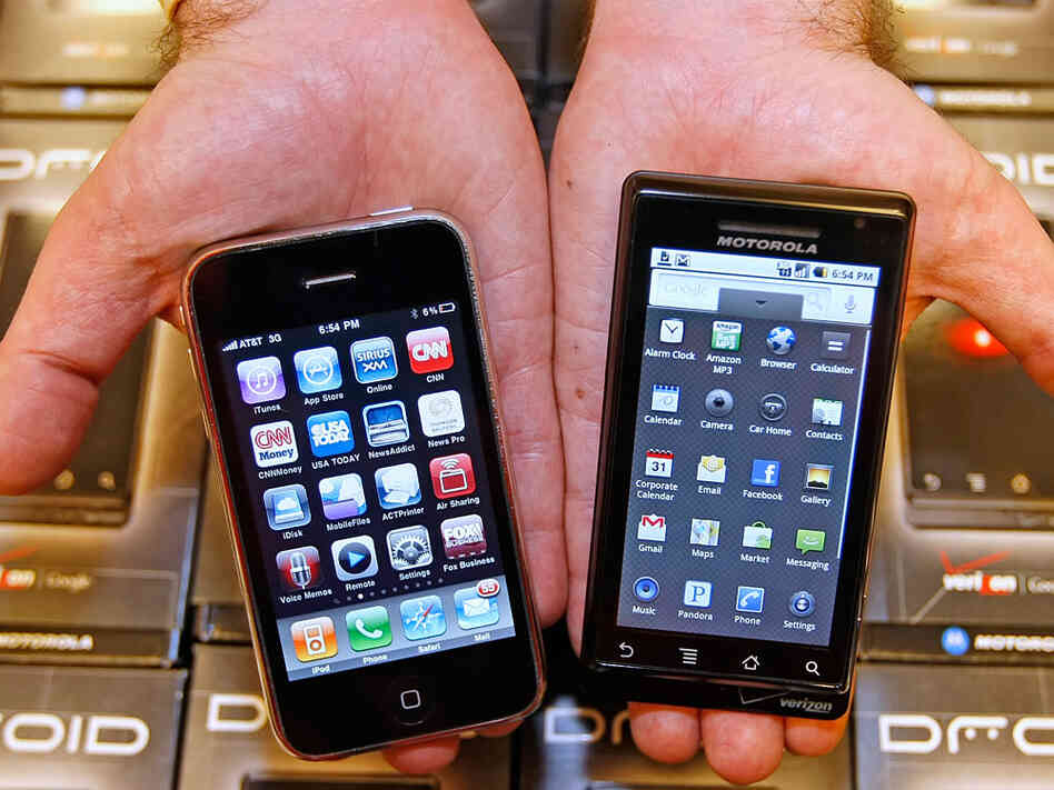 A manager holds an Apple iPhone and Motorola's Droid smart phone
