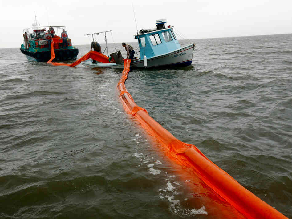 Out-of-work fishermen lay oil booms in preparation for the looming oil spill.