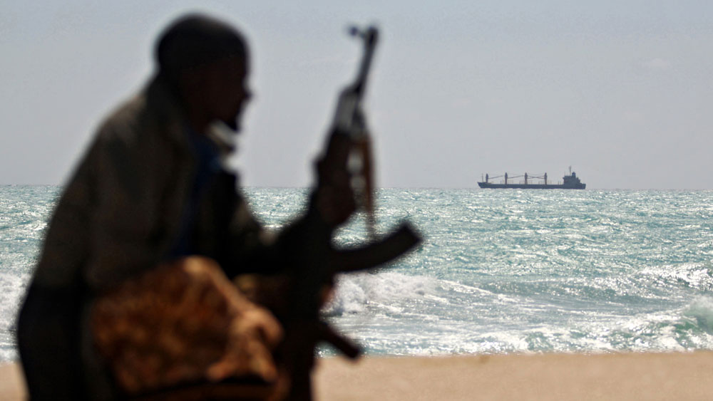 An armed pirate on the Somali coast watches a Greek cargo ship in January.