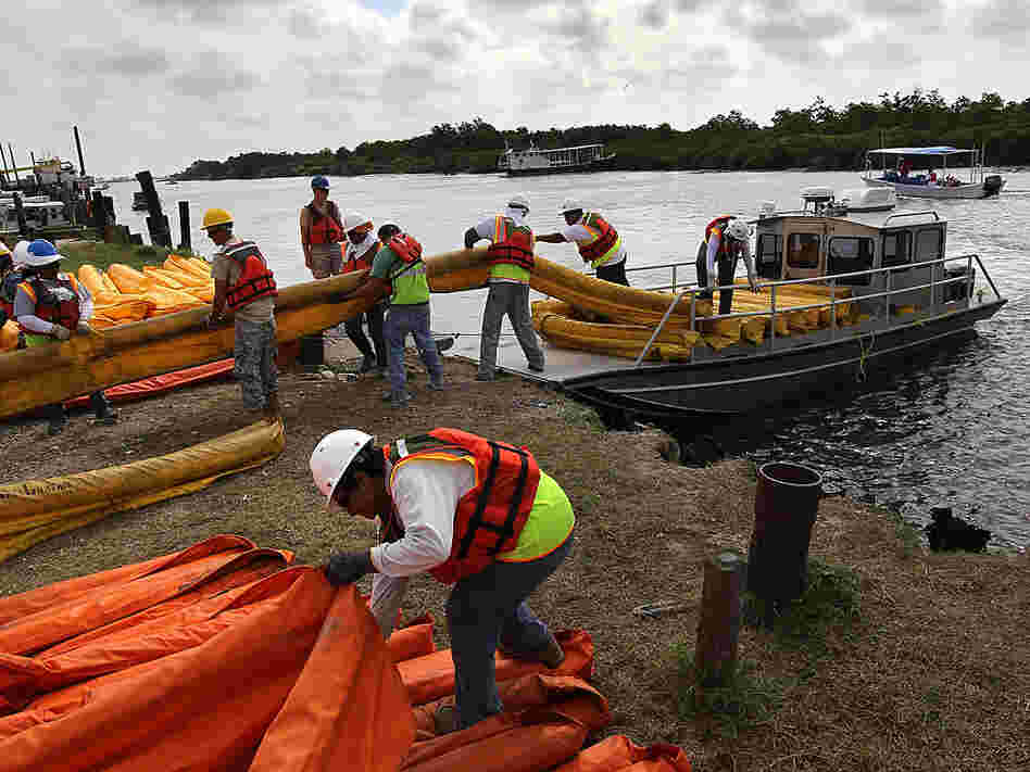 Contract workers load oil booms onto a boat to protect marshlands from the Gulf's massive oil slick.