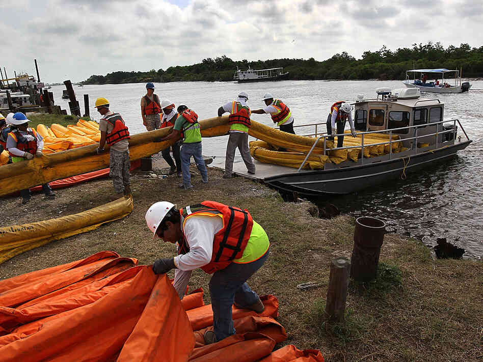 Contract workers load oil booms onto a boat to protect marshlands from the Gulf's massive oil slick.