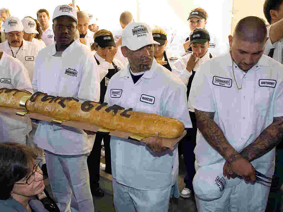 Homeboy Industries Bakery workers hold a giant loaf of bread.