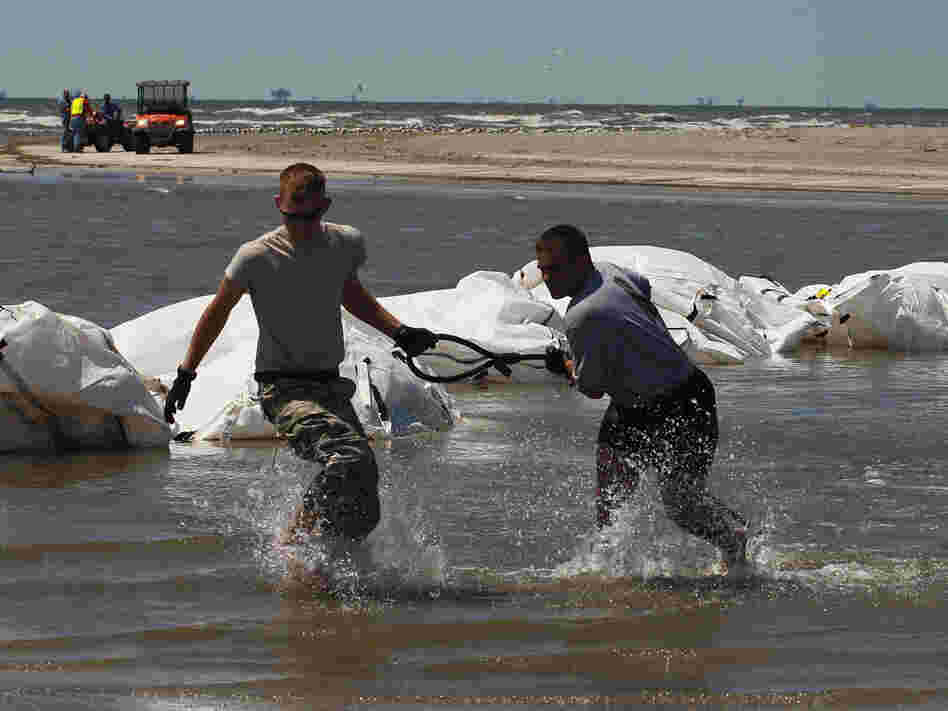 Louisiana National Guard members retrieve a cable attached to sand bags.