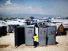 A little boy plays near four unused portable toilets A little boy plays near four unused portable toilets