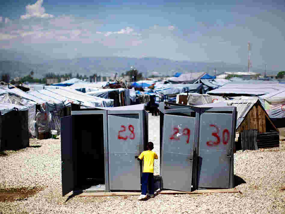 A little boy plays near four unused portable toilets