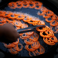 A street vendor fries jalebi, a treat made of batter and crystallized in sugar.