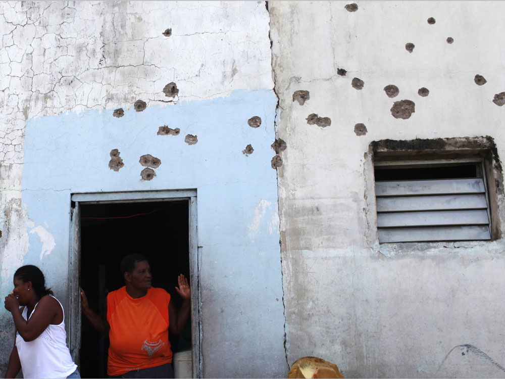 Tivoli Gardens residents gather outside their bullet-ridden home