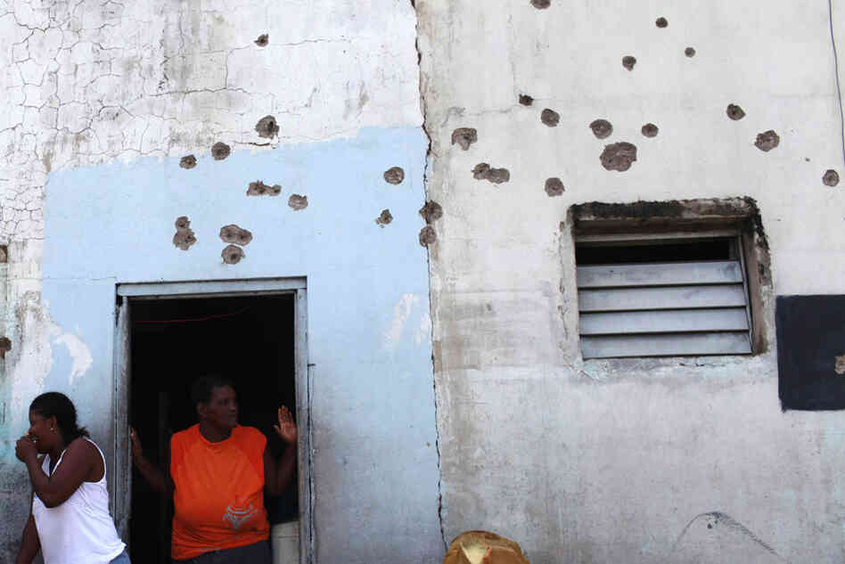 Tivoli Gardens residents gather outside their bullet-ridden home