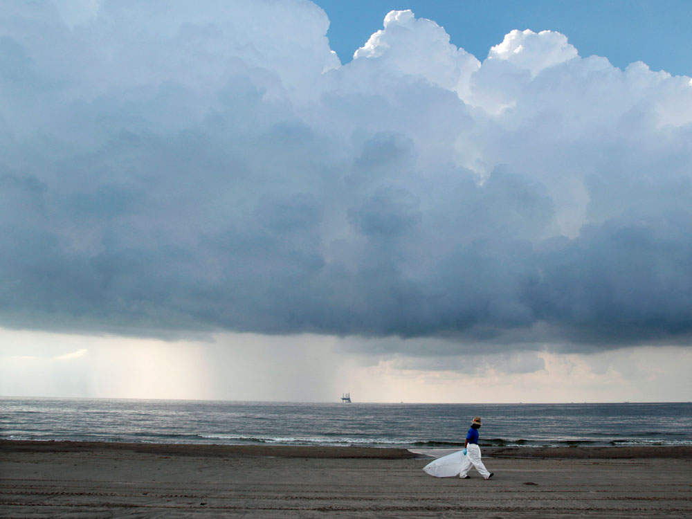 A worker leaves the beach as storm clouds approach Sunday in Grand Isle, La.