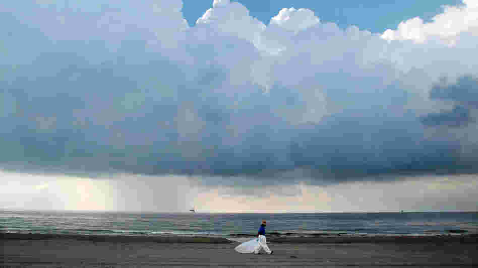 A worker leaves the beach as storm clouds approach Sunday in Grand Isle, La.