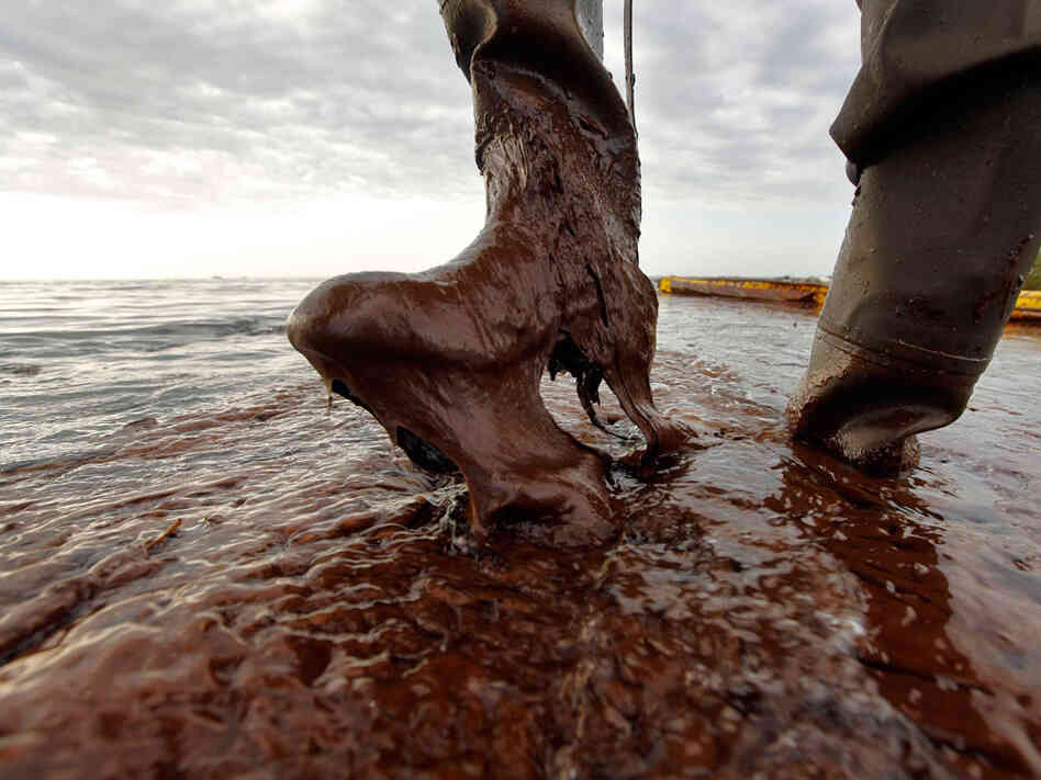 An official in Louisiana's Plaquemines Parish lifts his boot out of thick oil at Queen Bess Island.