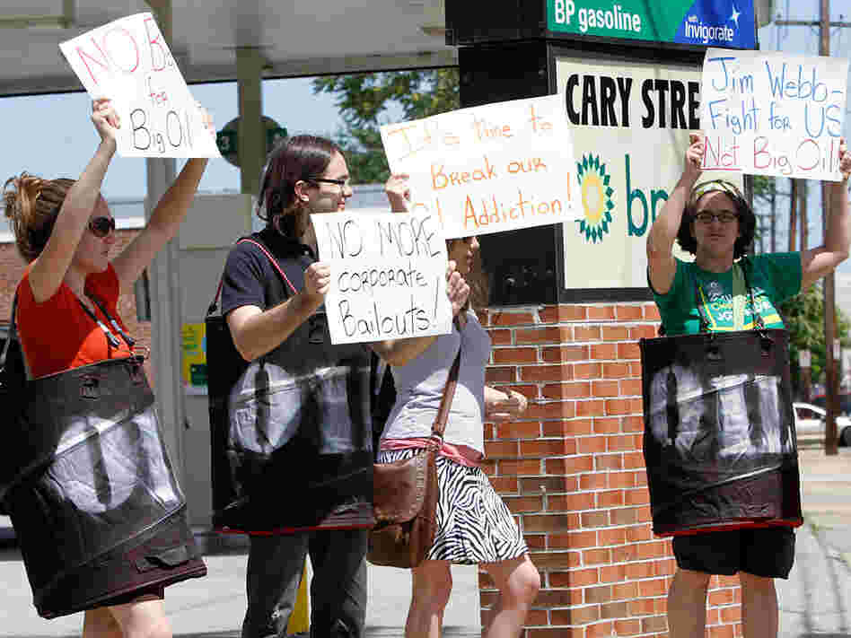 Protesters holds signs in front of a BP gas station in Richmond, Va., on Tuesday.
