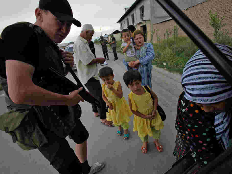 A Kyrgyz army volunteer checks the trunk of passing car during a search for weapons