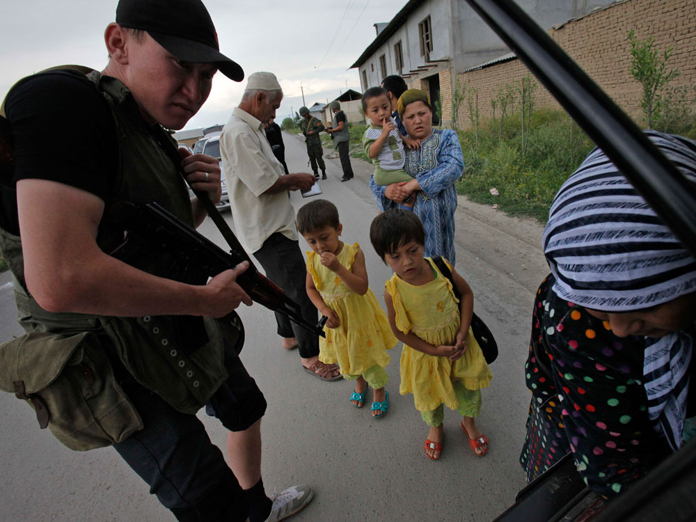 A Kyrgyz army volunteer checks the trunk of passing car during a search for weapons