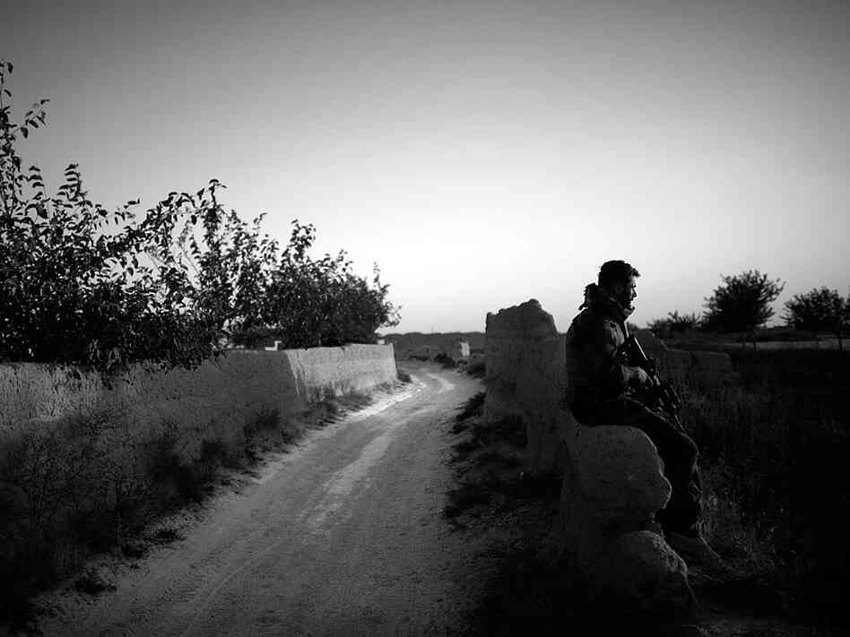 An Afghan commando sits on a mud wall