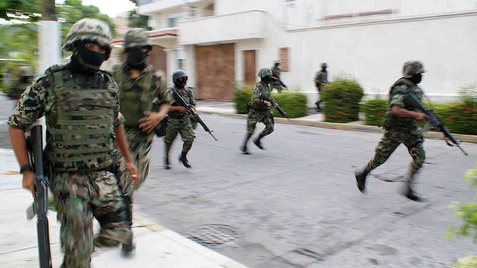 Mexican navy marines run down a street after a gun battle erupts in Acapulco.