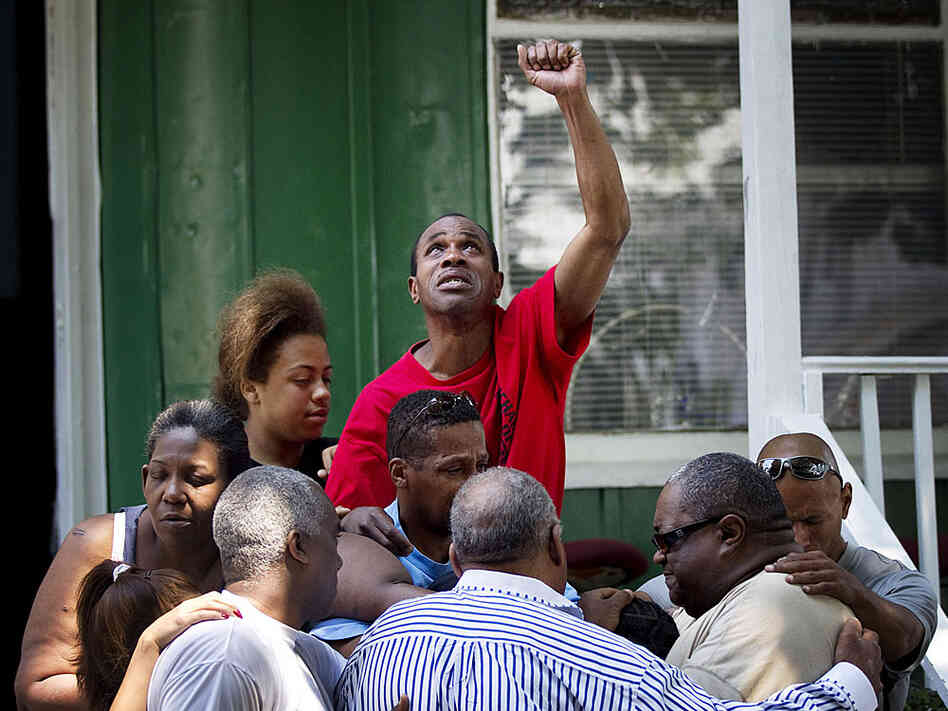 Nathaniel Davis (in tan shirt, right) grieves with neighbors after his 14-year-old son was shot.