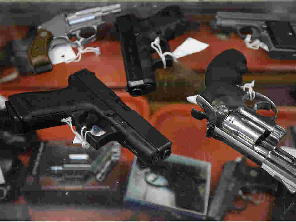 Semi-automatic handguns and revolvers are seen on top of a glass display case at John Jovino Co.