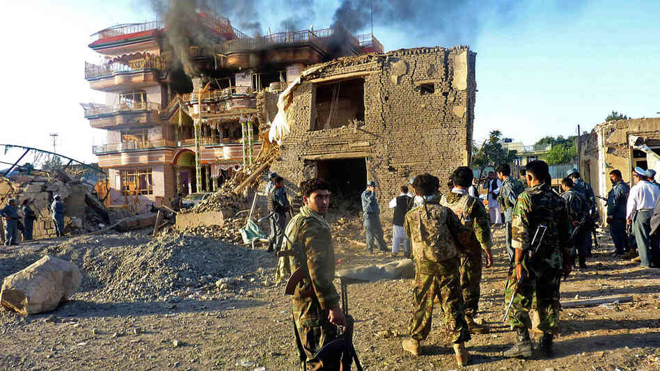 Afghan security forces stand outside a USAID compound after it was stormed by militants.