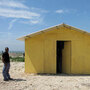 A guard stands outside a prototype "transitional" housing model at a resettlement camp.